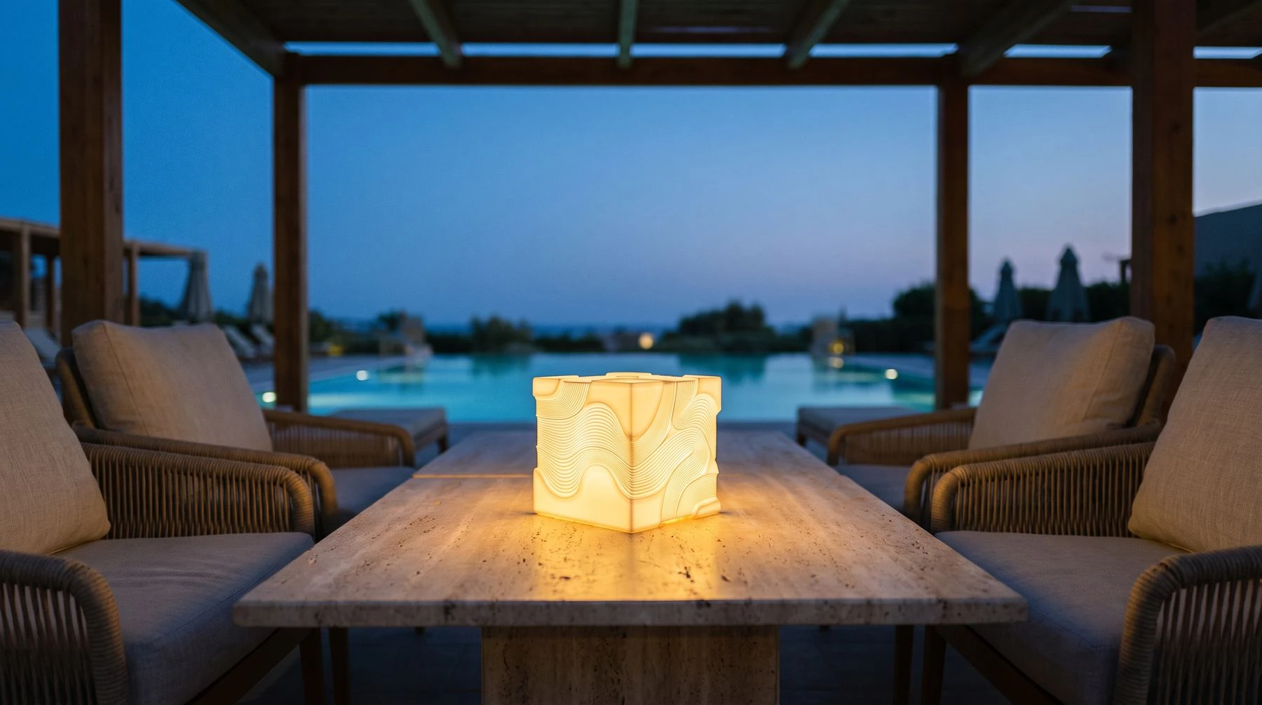 Candeeiro Ria numa mesa de esplanada, com a piscina ao fundo ao anoitecer